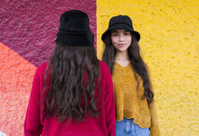 Smiling Young Woman Standing By Sister Facing Colorful Wall