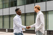 © Westend61 - Young man doing handshake with friend on footpath
