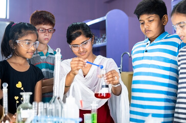 pan shot of teacher explaining about science experiment to students with eye protection glasses at c
