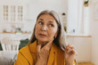 © shurkin_son - Elderly woman feeling pain, swollen thyroid or lymph nodes. Mature lady unwell staying at home, visit doctor for checkup. Problems with health, unwell, pain, hurting, healthcare concept