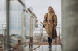 © Petro - Young business woman in coat standing outside
