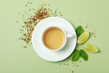 Concept of hot drink with buckwheat tea on green background