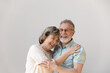 © fizkes - Sincere laughing bonding happy middle aged senior married couple cuddling, having fun enjoying communicating, isolated on white wall, showing candid loving feelings, good family relations concept.