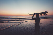 Silhouette Of Beautiful Sexy Surfer Female With Surfboard On The Sandy Beach At Sunset. Water Sports. Surfing Are Healthy Active Lifestyle. Summertime Vacation. Retro Color Effect.