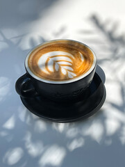 Wall Mural - A cup of cappuccino on a white table. Latte art, a flower made of milk froth. Coffee drinks photography.