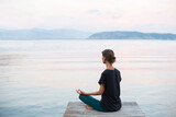 Fototapeta  - Beautiful woman practicing yoga near the sea, Young girl meditate at sunset, Harmony, meditation, healthy lifestyle and travel concept