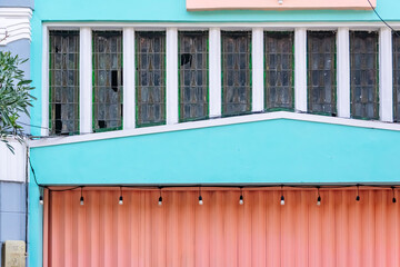 Fancy tosca blue wall from old vintage building with pink garage door from the colonial architecture under the bright blue sky