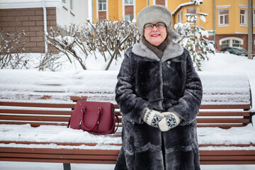 Wall Mural - An elderly woman sits on a city bench.