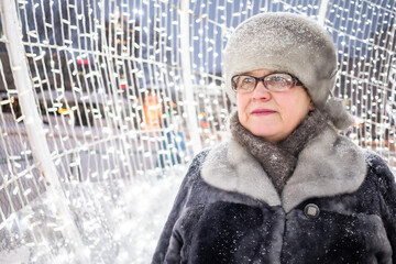 Wall Mural - Grandmother in glasses with a luminous garland in the background.