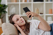 © DragonImages - Young woman relaxing on sofa and reading posts on social media on smartphone screen