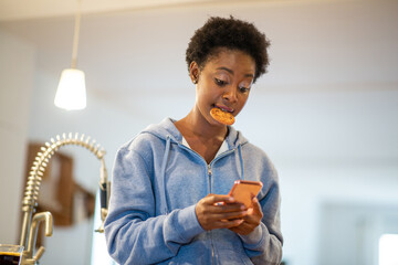 young african American woman with mobile phone and cookie in mouth