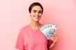 © Asier - Young caucasian woman holding banknotes isolated on pink background happy, smiling and cheerful.