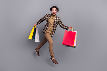 Sticker - Photo of pretty impressed man wear plaid shirt jumping running holding bargains isolated grey color background