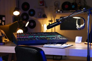 Microphone near table with professional mixing console in radio studio