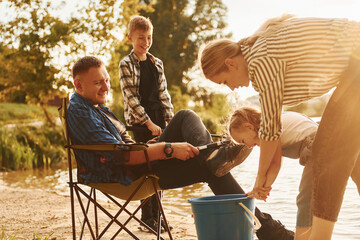 Wall Mural - Big catch. Father and mother with son and daughter on fishing together outdoors at summertime