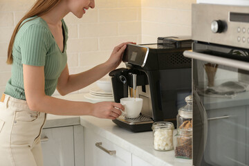 Wall Mural - Young woman preparing fresh aromatic coffee with modern machine in kitchen, closeup