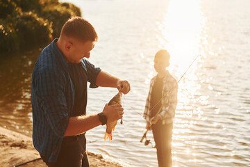 Wall Mural - With catch. Father and son on fishing together outdoors at summertime