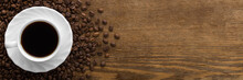 White Cup Of Black Coffee With Brown Beans On Dark Wooden Table Background. Closeup. Wide Banner. Empty Place For Text. Top Down View.