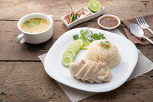 Sliced Hainan-style Chicken With Marinated Rice Served With Chilli Sauce And Cucumber In White Plate.Asian Food Style