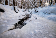 Frozen Small Brook Stream In Winter Covered With Ice And Snow
