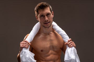 Wall Mural - After workout. Confident caucasian sportsman with towel on shoulders looking at camera over brown background