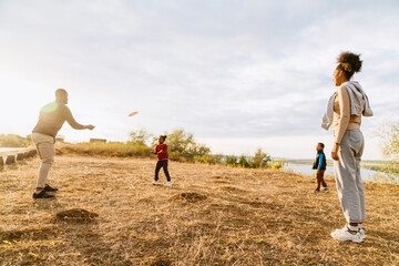 Wall Mural - Black family laughing and playing with frisbee during walking