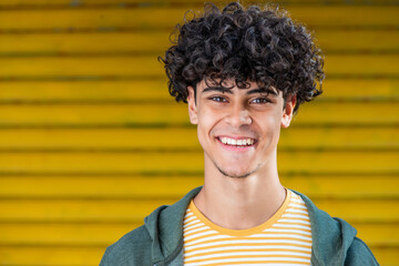 Close up young arabic man smiling by yellow background