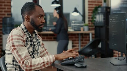 Static portrait of african american system engineer working focused looking at computer screen while typing. Software developer in server room writing innovating artificial intelligence algorithm.