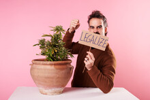 A Young Man With A Sign "legalize Cannabis" On Pink Background