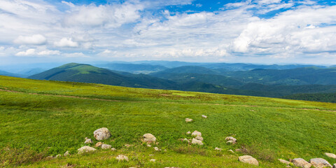 beautiful view of green mountain landscape. sunny outdoor nature scenery in summer. stones on the grassy hill. clouds above ridge on horizon in the distance