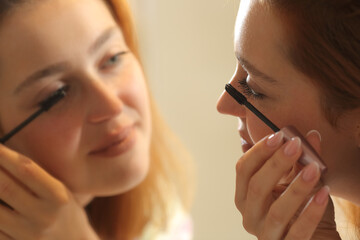 Wall Mural - Woman painting eyelashes looking in mirror