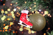 Wooden Skates With A Golden Ball On A Green Christmas Tree, With A Beautiful Bokeh