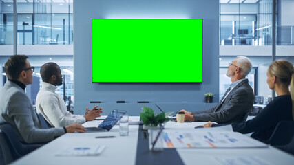 Wall Mural - Office Conference Room Meeting using Video Call: Diverse Team of Successful Managers, Executives Talk, Use Green Screen Chroma Key TV. Businesspeople Work on Strategy for an e-Commerce Startup