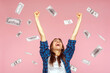 © khosrork - Money rain, winner and rich. Hurray. satisfied happy young woman rising hands up with toothy smile on face, pleased, amazed with money falling. Indoor studio shot isolated on pink background
