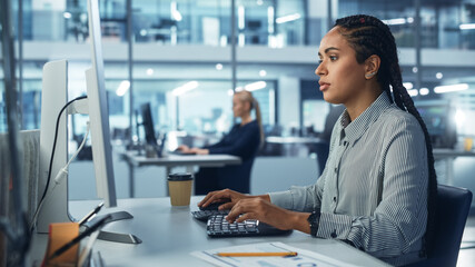 Corporate Office: Black Female IT Technician Using Desktop Computer, Uses Big Data Statistics, Graphs. Smiling Creative Software Engineer Work on eCommerce Project Marketing, Development.