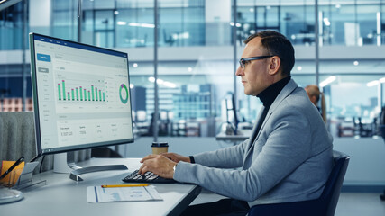 Leinwandbilder - Diverse Corporate Office: Stylish Handsome Big Data Engineer Using Desktop Computer, Screen Showing Graphs, Statistics, Company Growth. Businessman Working on e-Commerce Project Marketing, Development