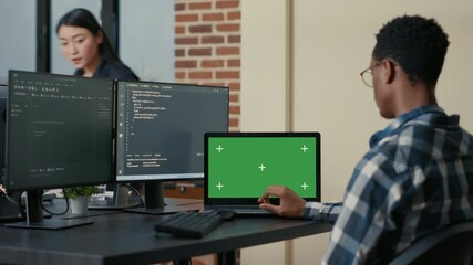 Database designer writing code using laptop with green screen chroma key mockup sitting at desk in busy developers agency. Programer looking at multiple screens with programming language.