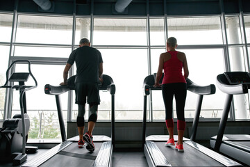 Wall Mural - Active lifestyle. Middle-aged couple walking on treadmills