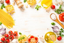Italian Food Background On White Kitchen Table. Raw Pasta, Olive Oil, Spices, Tomatoes And Basil. Food Frame. Top View With Copy Space.