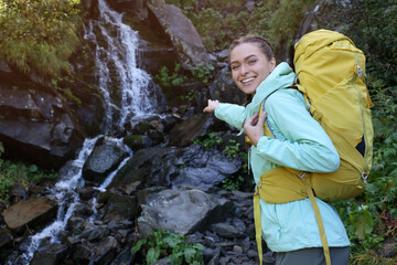 Sticker - Tourist with backpack near waterfall in mountains. Space for text