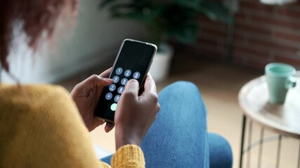 Wall Mural - Video of  back of young woman using her mobile phone while sitting on sofa at home.