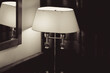 A lit table lamp with a white shade on the nightstand