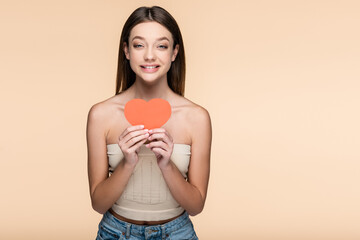 Canvas Print - happy young woman in crop top holding red paper heart isolated on beige