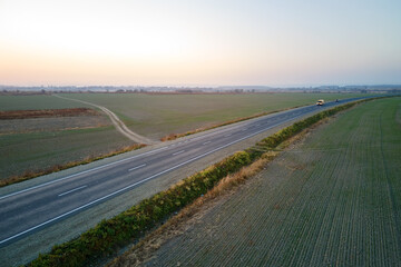 Canvas Print - Aerial view of empty intercity road at sunset. Top view from drone of highway in evening