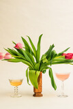 Fototapeta Tulipany - cocktails drinks with pink tulip bouquet in brass vase against warm white background