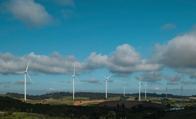 Eco power, landscape with hills and wind turbine field on blue sky background.