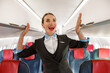 © Kostiantyn - Joyful stewardess standing in airplane passenger salon