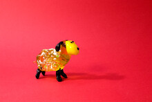 Miniature Glass Yellow Lamb Or Sheep Figurine Isolated On Red Background