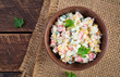 Salad with corn and crab sticks in bowl on wooden table. Traditional Russian cuisine.Top view, overhead
