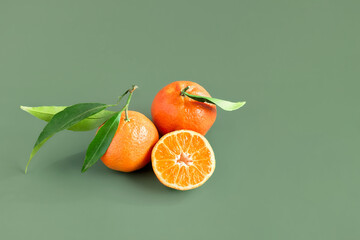 Wall Mural - Fresh ripe juicy tangerines with leaves on light green background. Citrus fruits for healthy eating and natural vitamins. Creative fruit.